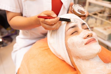 young woman with facial mask at beauty spa salon