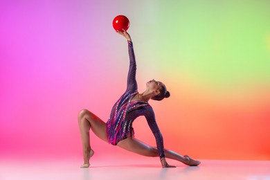 young graceful girl, female rhythmic gymnast training, exercising with red ball isolated over multicolored neon background. copyspace for ad. side view