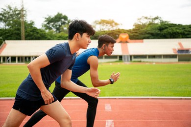 two young asian men athlete preparing starting running and training on the track in stadium