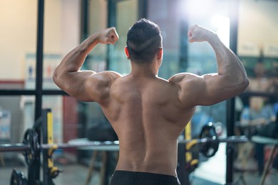 unidentified shirtless adult asian men sweating while lift up the barbell workout machine for muscle part inside of fitness gym. bodybuilding athlete sport training for body strength and good health.
