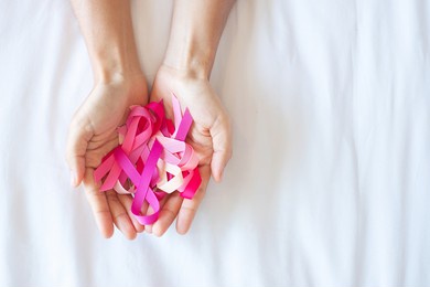 october breast cancer awareness month, adult woman  hand holding pink ribbon on pink background for supporting people living and illness. international women, mother and world cancer day concept