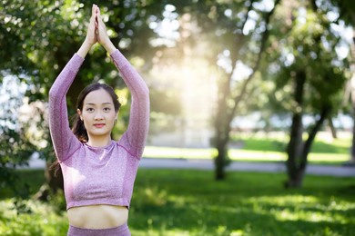 young asian woman doing yoga fitness exercises in the nature park, exercise for health or warm-up body, fresh air, or oxygen in the green tree in the park in sunlight.