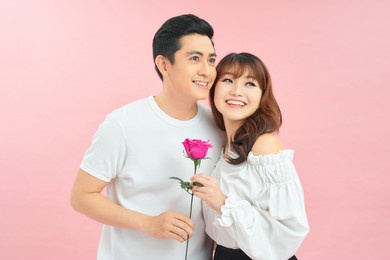 lovely couple holding flower on pink background