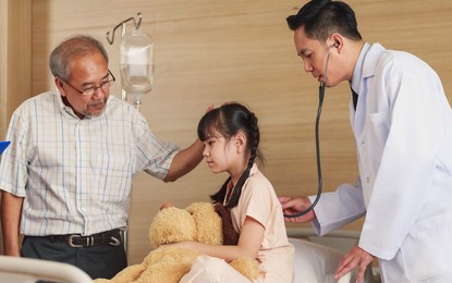 asian pediatrician man doctor consulting sick girl patient listening lungs using medical stethoscope during disease examination in hospital ward. hospitalized little child recovering after surgery.