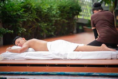 asian man enjoy a massage by the resort's pool. 