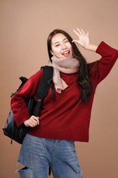 asian tourist woman backpacker, winter outfit wear red sleeves and pink scarf, brown background