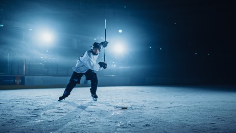 ice hockey rink arena: professional player shooting, hitting, stricking the puck with hockey sticks. athlete scoring a goal. dramatic wide shot, cinematic lighting.