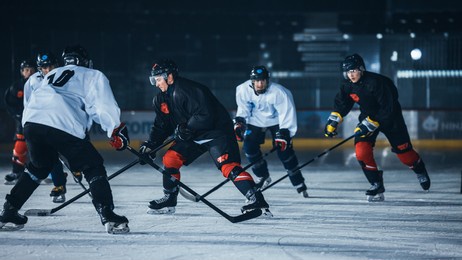 dark ice hockey rink arena: young players training, learning stick and puck handling. athletes learn how to dribble, attack, defend, protect, possesion, drive the puck.
