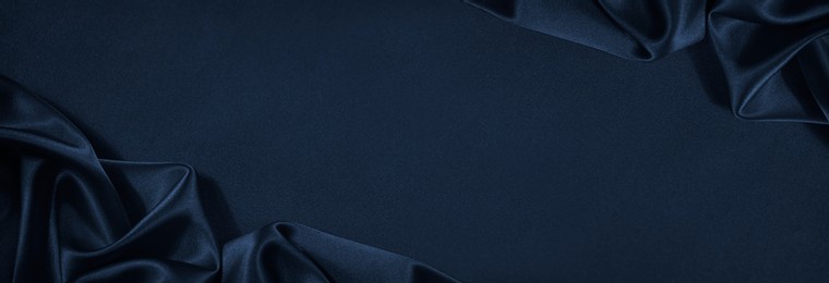 beautiful dark blue silk satin background. soft folds on shiny fabric. luxury background with copy space for text, design. web banner. flat lay, top view.
