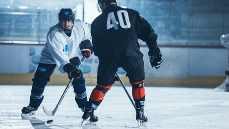 ice hockey rink arena: two professional players from different teams fighting for the puck with stick during championship. athletes play intense game wide of energy competition.