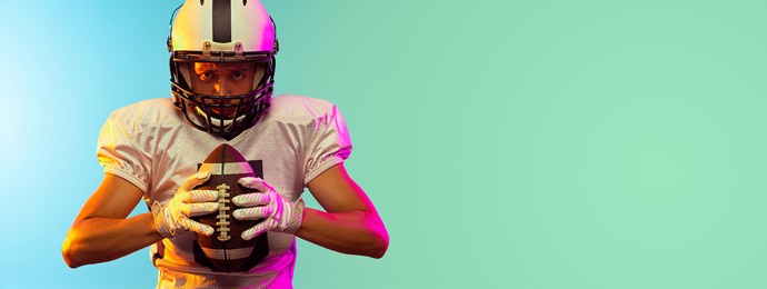 energy. close-up portrait of male american football player playing, training isolated on blue background in neon light. concept of sport, movement, achievements. copy space for ad. flyer