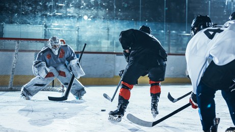 ice hockey rink arena: professional forward player masterfully dribbles, breaks defense, ready to hit the puck with stick to score a goal. important and tension moment.
