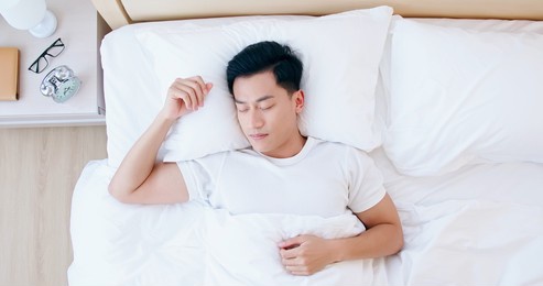overhead view of young asian man sleeping well and relaxing in the morning