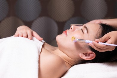 young woman with facial mask at beauty spa salon
