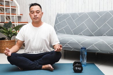 asian man practicing yoga or meditation at home