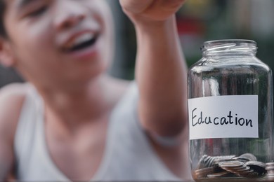 "education" text on a piggy bank with thai coins,blurred background of asian special need child on wheelchair saving money for education,learning in the future, happy disabled kid concept.