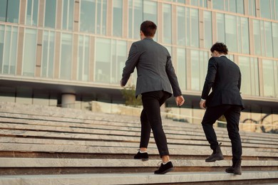 two male entrepreneurs have interesting ideas for the future project. friends, managers and colleagues are creating a new startup. business suits, work near the office on the street.