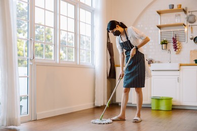 young asian woman washing floor with mop in the kitchen. beautiful young female makes cleaning the kitchen. women doing housework, housewife portrait.