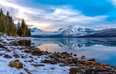 snow on the shore of a mountain lake. mountain lake landscape. snowy mountain lake view. lake in snowy mountains