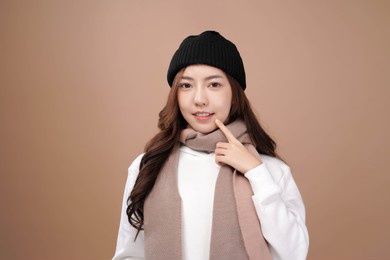 asian woman with winter outfit wear pink scarf, mocha brown background