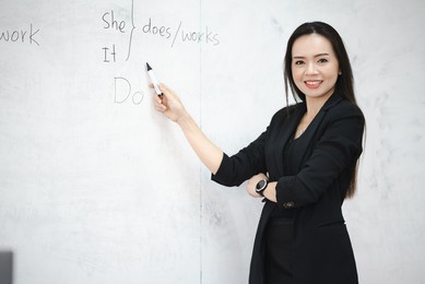 a middle-aged asian woman teacher in classroom white board at university