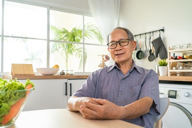 portrait of senior male smile and look at camera in kitchen at home. strong elderly older grandfather wear eyeglasses, feel happy and enjoy retirement life in house. health care and medical concept.