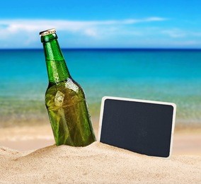 beer bottle in the sand on the beach and a blackboard for writing