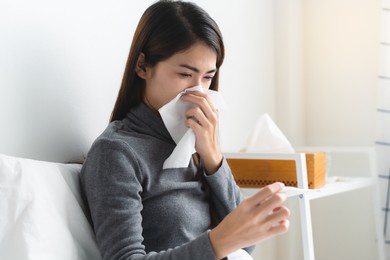 sick day at home in winter season. young asian woman lying on the bed have a fever and her husband checking thermometer and measure body temperature.