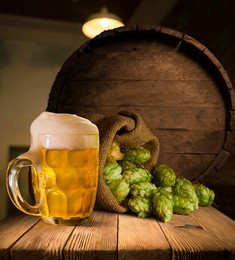 beer brewing ingredients hop in bag and wheat ears on wooden cracked old table. beer brewery concept. hop cones and wheat closeup. sack of hops and sheaf of wheat on vintage background.