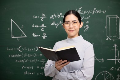 young asian teacher woman teaching holding book and video conference with student looking camera. female teacher training the mathematics in classroom blackboard from online course.