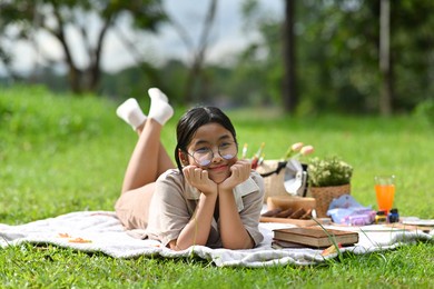 portrait with asian adolescent lying on the lawn and her hands on chin , out door activity and picnic.