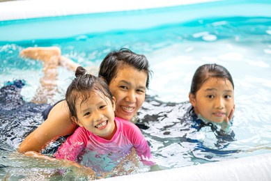 portrait photo of asian family in swimming suit playing in inflatable pool at home in summer vacation day. family, asian family, lifestyle concept 