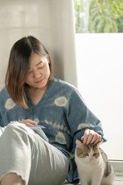 asian woman smile and happy during play with her cat and use tablet meeting and working from home