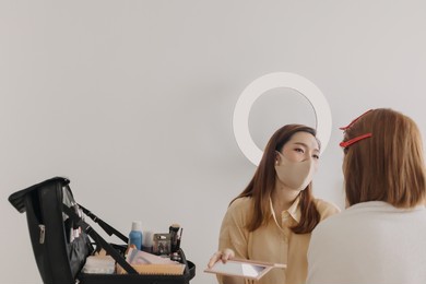 asian woman makeup artist is at work and wearing makeup on her model.