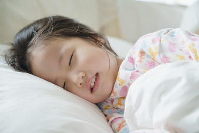 scene of close up sleeping child in the bed at the morning natural light. asian toddler girl sleep.