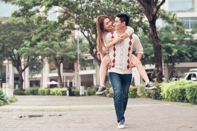 young man carrying his girlfriend on the back in the park