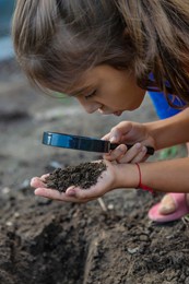 the child examines the ground with a magnifying glass. selective focus. nature.