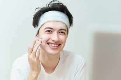 young man applying cream to his face