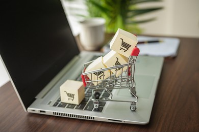 papers with a shopping cart logo on a cart with a laptop .shopping service on the online web and offers home delivery. shopping online concept.
