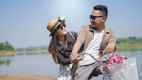 happy young couple cycling with blue sky in summer