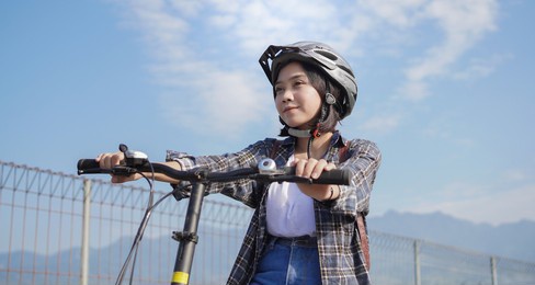 young asian woman ride break bicycle background blue sky