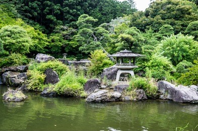 a lamp overlooks the pond in the garden at narita temple