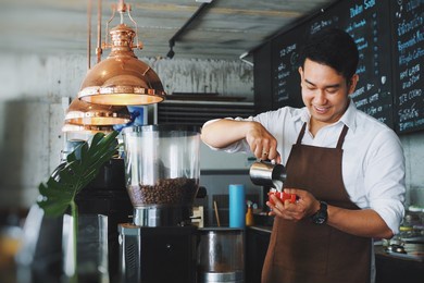 smiling asian man barista working at cafe.
