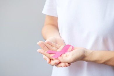 october breast cancer awareness month, elderly woman in white t- shirt with hand holding pink ribbon for supporting people living and illness. international women, mother and world cancer day concept