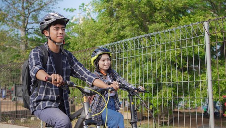 young asian couple ride bicycle together go to work