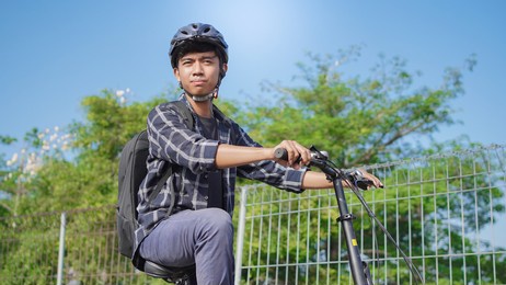 asian young man with backpack having rest after ride bicycle 
