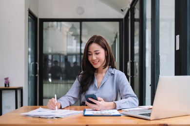 business asian woman using smartphone for do math finance on wooden desk in office, tax, accounting, financial concept