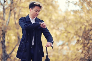 autumn park in rainy weather and a young man with an umbrella
