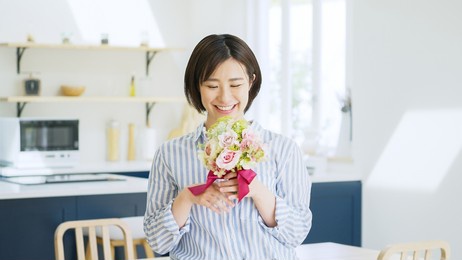 a smiling asian woman with a bouquet