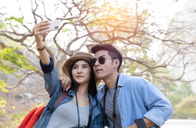 asian couple taking selfie with smartphone while trekking in national park